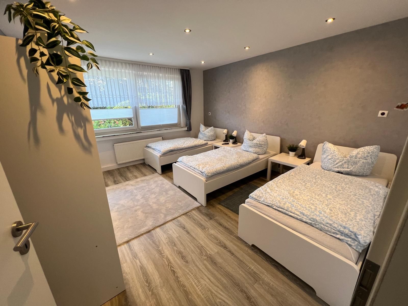 Sehr ansprechendes Mehrbett-Schlafzimmer mit drei gemachten Einzelbetten, guter Belichtung, Vorhängen und großzügigen Raumverhältnissen — ideal für mehrere Monteure.